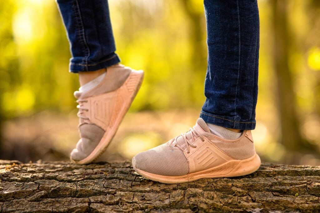 Pies de un niño con zapatillas deportivas caminando sobre un tronco en el bosque