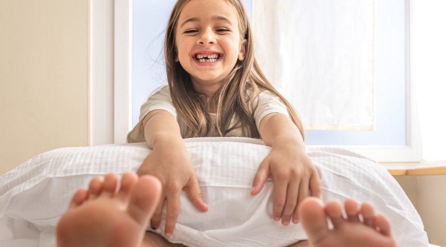 Adorable little girl with pillow in bed early in the morning, copy space.
